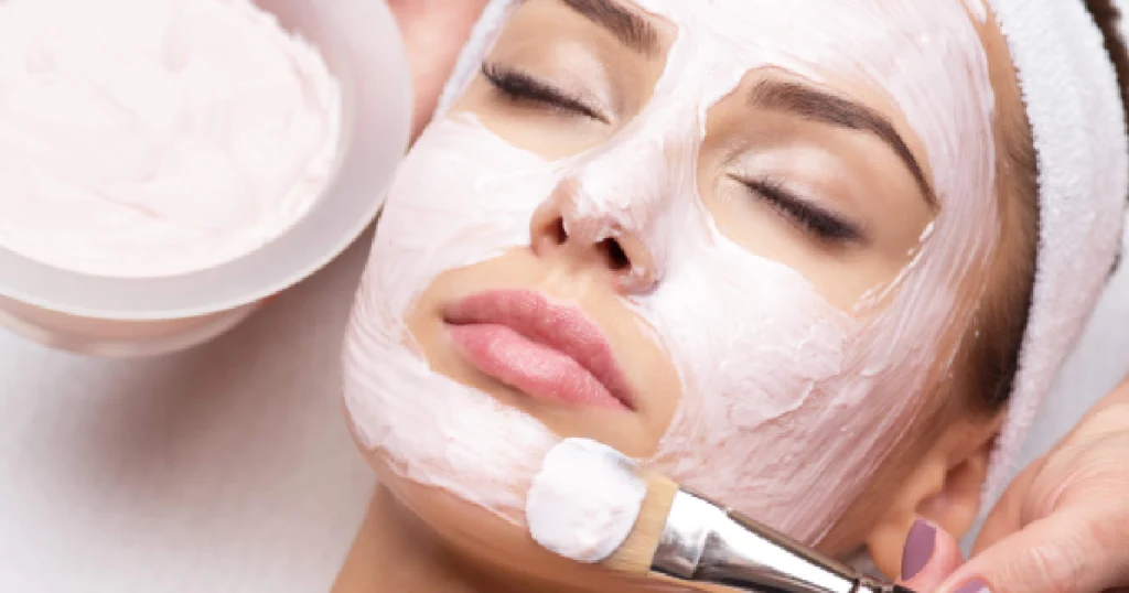Woman getting a Glo2Facial with a pink cream mask applied by brush in Ormond Beach, FL