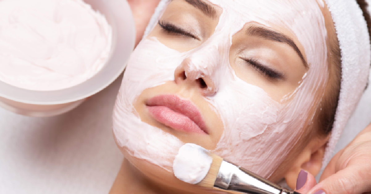 Woman getting a Glo2Facial with a pink cream mask applied by brush in Ormond Beach, FL